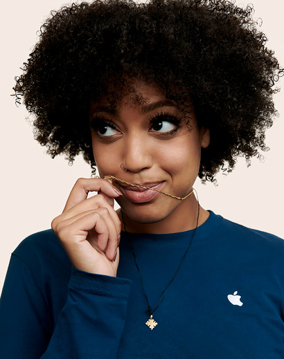 Apple Retail employee with shoulder-length curly hair, smiling at the camera.