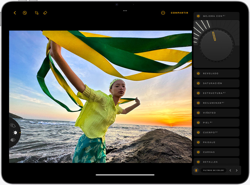 iPad Air en horizontal que muestra la foto de una chica que sujeta unas cintas amarillas y verdes con un atardecer en el mar de fondo