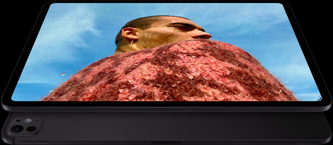 Vooraanzicht van iPad Pro in de kleur Spacezwart, in horizontale stand, afgeronde hoeken, zwarte rand rond display, display met een foto van een man in een rode trui onder een blauwe lucht, eronder een andere iPad Pro in de kleur Spacezwart in horizontale stand, pro-camerasysteem, volumeknoppen