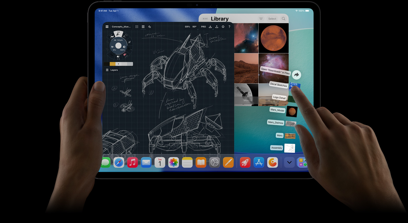 Vooraanzicht van iPad Pro, horizontale stand, rechterhand beweegt over de map Downloads met bestanden die in een waaier worden weergegeven, display toont iPadOS 26-interface met meerdere geopende apps, waaronder een fotobewerkingsapp met gedetailleerde robotontwerpen, handgeschreven annotaties, meerdere ontwerpfasen en de fotobibliotheek