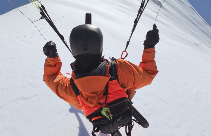 شخص يحلّق بمظلة في الهواء عبر قمة جبل كبيرة في فيديو بمجال رؤية واسع